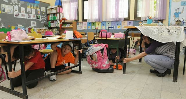 תלמידים בבית הספר גורדון מסתתרים מתחת לשולחן בעת תרגיל של פיקוד העורף