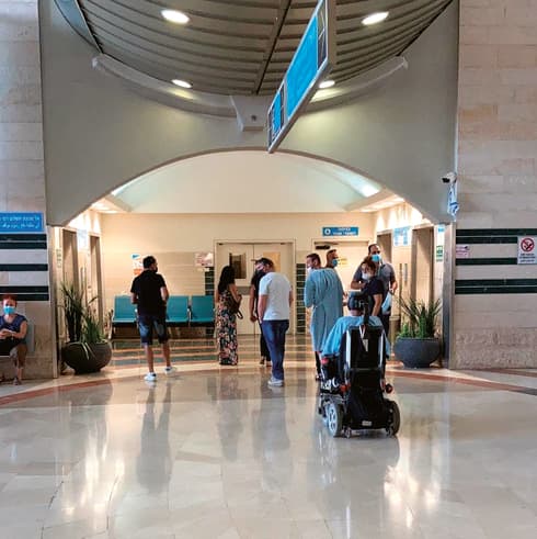 תשעה אנשים ממתינים בתור למעליות בבית החולים