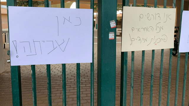 שלטים על השערים הסגורים של בית הספר