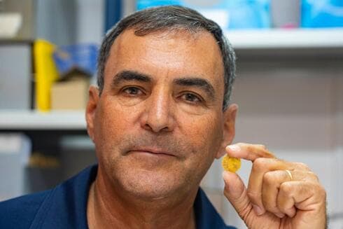 יואב לרר, מנהל החפירה, עם אחד ממטבעות הזהב