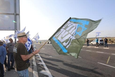 מפגין עם דגל אחים לנשק (צומת: ענת חרמוני) המחאה בצומת נהלל