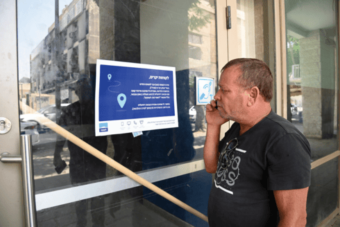 לקוח מופתע מול סניף הבנק שנסגר