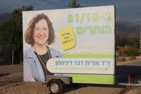 שלט בחירות של אורית דגני דיניסמן בכניסה לקיבוץ דפנה