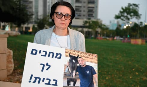 קטיה בייזר עם תמונת בנה ניק ז"ל במהלך מאבקה להשבתו