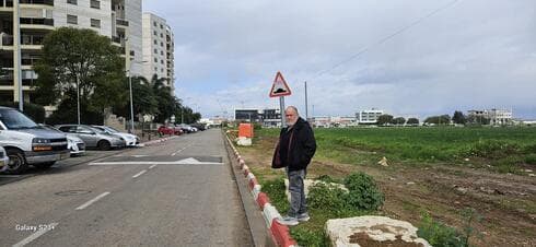 מוטי אפרתי ליד הבניינים בשכונת חן הצפון והשטח עליו אמור לקום הדיפו של המטרו (צילום: פרטי) מוטי אפרתי ליד הבניינים בשכונת חן הצפון והשטח עליו אמור לקום הדיפו של המטרו