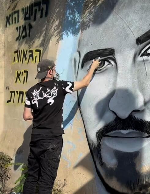 הצייר איתי ארד בעת צביעת הקיר