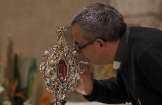 Un peregrino cristiano toca un pequeño trozo de una reliquia de madera 