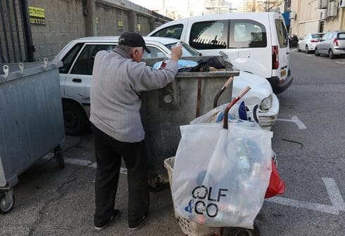 Un anciano busca botellas de plástico en la basura para intercambiarlas por dinero