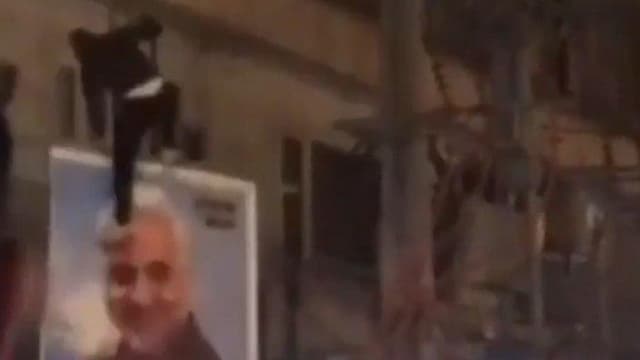 Un manifestante quita un póster de Soleimani