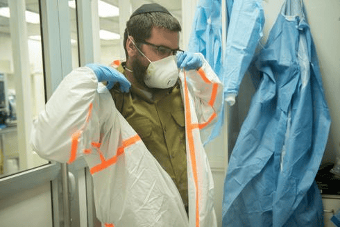 Un soldado de las FDI se pone un equipo de protección en un laboratorio militar que investiga el tratamiento del coronavirus. (Unidad del Portavoz de las FDI) Un soldado de las FDI se pone un equipo de protección en un laboratorio militar que investiga el tratamiento del coronavirus.