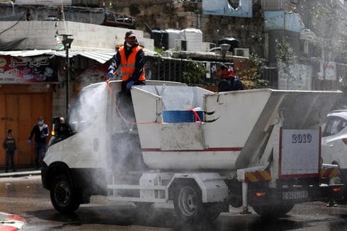 Empleados del municipio palestino rocían desinfectante en la ciudad de Hebrón. 