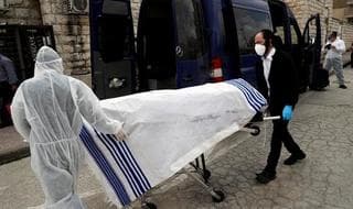 Los trabajadores de la Sociedad Judía de Entierro usan equipo de protección mientras llevan el cuerpo de una víctima de la enfermedad por coronavirus (COVID-19) para ser enterrado en Jerusalem. 