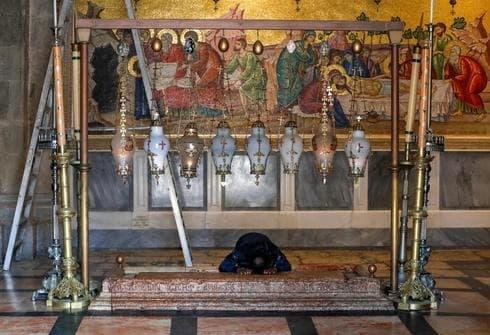 Un adorador solitario reza por la Piedra de la Unción en la Iglesia del Santo Sepulcro en la Ciudad Vieja de Jerusalem. (AFP) Un adorador solitario reza por la Piedra de la Unción en la Iglesia del Santo Sepulcro en la Ciudad Vieja de Jerusalem.