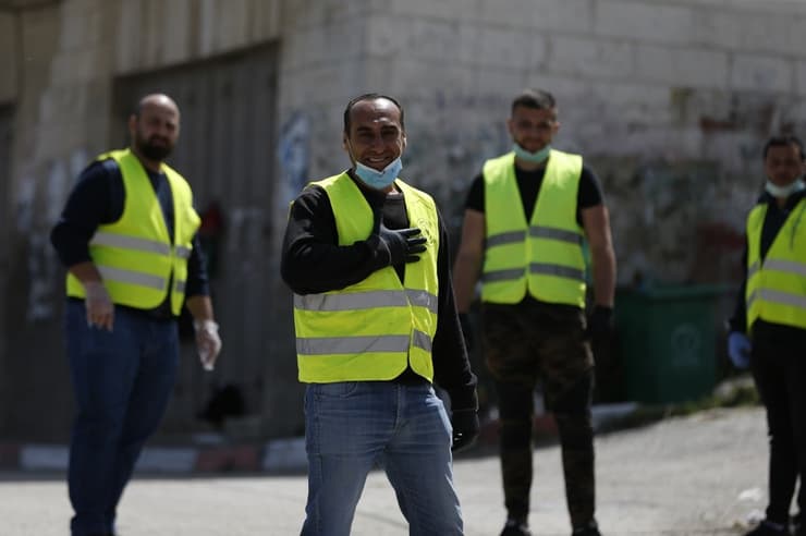 Con mascarillas y chaleco amarillo, los voluntarios palestinos controlan la entrada a las aldeas de Judea y Samaria. 