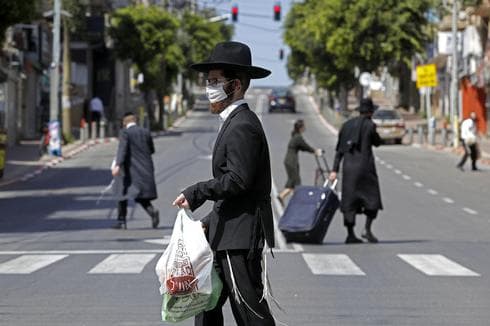 Hombre ultra ortodoxo con máscara protectora realiza compras y camina por las calles de Bnei Brak. (AFP) salud coronavirus