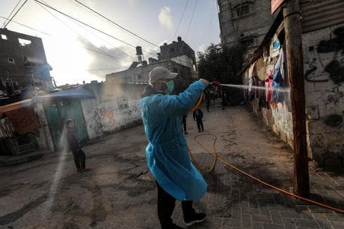 Los palestinos rocían desinfectante como precaución contra la propagación del coronavirus Covid-19, en las calles del campo de refugiados de Al Nusairat, en el centro de la Franja de Gaza. 