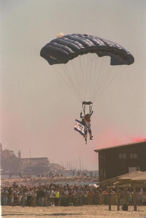 Tradición que aún continúa: un paracaídista baja con la bandera israelí en la playa de Tel Aviv, 2004. (Moshe Milner, Oficina de prensa, gobierno de Israel) Tradición que aún continúa: un paracaídista baja con la bandera israelí en la playa de Tel Aviv, 2004.