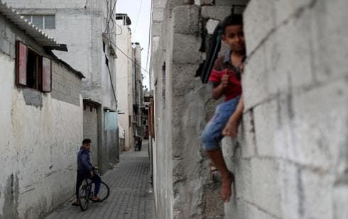 Un joven palestino en bicicleta observa a un niño sentado en una pared en el campo de refugiados de Jabalia. (Reuters) Un joven palestino en bicicleta observa a un niño sentado en una pared en el campo de refugiados de Jabalia.
