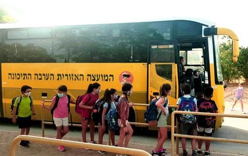 Alumnos israelíes abordan un autobús escolar cubriendo sus rostros con máscaras de protección. (Mirit Helman) Alumnos israelíes abordan un autobús escolar cubriendo sus rostros con máscaras de protección.