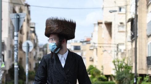 Un hombre ultraortodoxo usa una máscara facial en Bnei Brak, una de las ciudades más golpeadas por el coronavirus. (Nadav Abas) coronavirus estudio