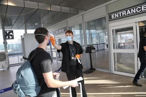 Guardia de seguridad verifica la temperatura de un pasajero a su llegada al aeropuerto Ben Gurion. 