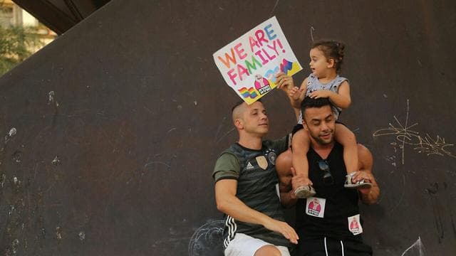Una pareja gay y su hija en una protesta de julio de 2019 en Tel Aviv contra la prohibición de la subrogación de parejas del mismo sexo. (Moti Kimchi) Una pareja gay y su hija en una protesta de julio de 2019 en Tel Aviv contra la prohibición de la subrogación de parejas del mismo sexo.
