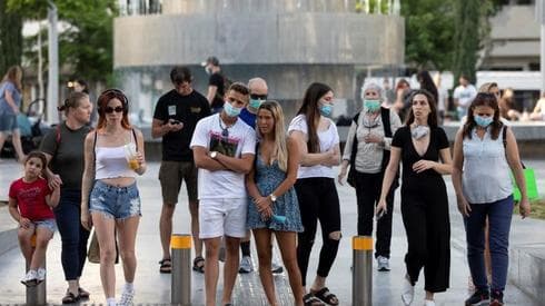 Los peatones, algunos con máscaras, se preparan para cruzar la calle en el Círculo Dizengoff de Tel Aviv. 
