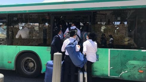 Gente intenta subir a un autobús ya repleto de pasajeros. 