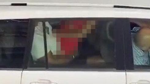 En el video se observa a una mujer con un vestido rojo sobre un hombre dentro de un vehículo de la ONU en Tel Aviv. (Captura de pantalla) En el video se observa a una mujer con un vestido rojo sobre un hombre dentro de un vehículo de la ONU en Tel Aviv.