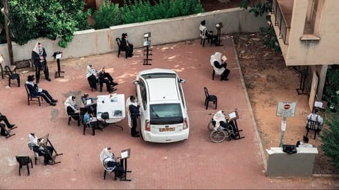 Rezo al aire libre y con distanciamiento social en Bnei Brak. 