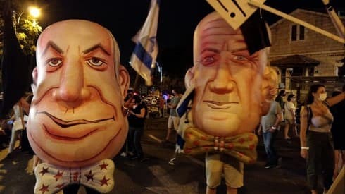 Manifestantes portan máscaras gigantes de Benjamín Netanyahu y Benny Gantz durante las protestas. 