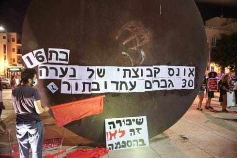 Manifestantes en el centro de Tel Aviv junto a una pancarta que dice: Violación en grupo de una niña de 16 años, 30 hombres hicieron fila. (Moti Kimchi) Manifestantes en el centro de Tel Aviv junto a una pancarta que dice: Violación en grupo de una niña de 16 años, 30 hombres hicieron fila.