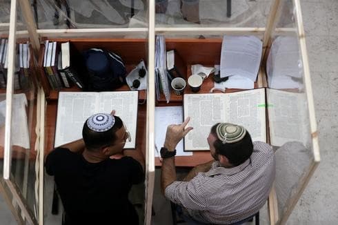 Dos estudiantes de la yeshivá dialogan sobre las escrituras separados por una lámina de plástico. (Reuters) Dos estudiantes de la yeshivá dialogan sobre las escrituras separados por una lámina de plástico.