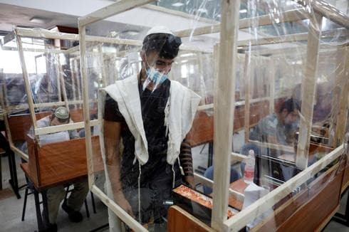 Los alumnos de la yeshivá Max y Ruth Schwartz rezan y estudian en escritorios rodeados de láminas de plástico. (Reuters) Los alumnos de la yeshivá Max y Ruth Schwartz rezan y estudian en escritorios rodeados de láminas de plástico.