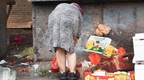 Una escena de Tel Aviv: una mujer revuelve la basura en busca de comida. (Nadav Abas) Una escena de Tel Aviv: una mujer revuelve la basura en busca de comida.