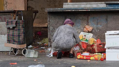 Una mujer buscando comida en la basura, cerca del mercado Carmel de Tel Aviv.