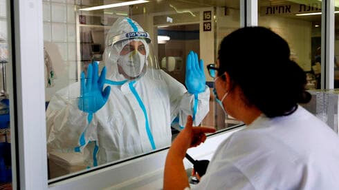 Equipo médico conversa a través de un vidrio en una sala de atención por COVID-19. (AFP) Equipo médico conversa a través de un vidrio en una sala de atención por COVID-19.