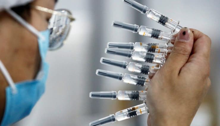 Científico chino sostiene varias dosis de vacuna contra el coronavirus. 