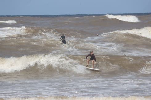 Jóvenes surfean en el mar negro de Tel Aviv.