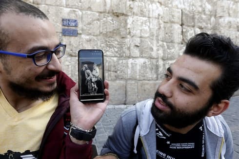En el teléfono móvil tiene la foto de otro dúo de discapacitados que se complementaban, hace un siglo. (AFP) Siria discapacitados