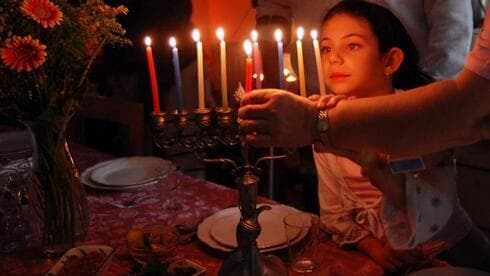 Una familia encendiendo la menorah en Janucá. 