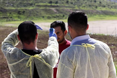 Trabajadores de la salud palestinos toman la temperatura de un hombre en Hebron. (EPA) Trabajadores de la salud palestinos toman la temperatura de un hombre en Hebron.