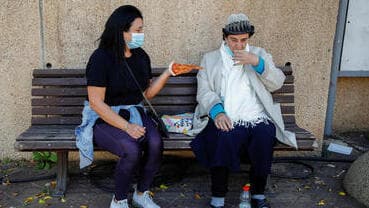 Una mujer come un porción de pizza luego de haber recibo la vacuna contra el COVID-19 en Tel Aviv. 