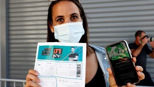 Una mujer junto a su entrada y el certificado de vacunación. 