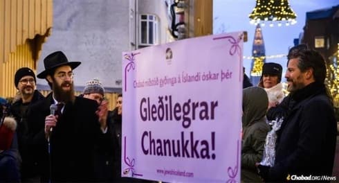 El rabino Avi Feldman habla en la ceremonia de encendido de la menorá gigante en el centro de Reykjavik. A la derecha, el alcalde de la ciudad. (Chabad.org) Judíos en islandia