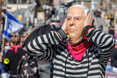 Un manifestante porta una máscara de Netanyahu durante una protesta frente al Tribunal de Distrito de Jerusalem, en febrero de 2021. (AFP) Un manifestante porta una máscara de Netanyahu durante una protesta frente al Tribunal de Distrito de Jerusalem, en febrero de 2021.