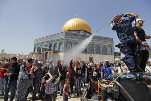 Un hombre rocía con agua fresca a los palestinos congregados en la Explanada de las Mezquitas. Atrás, la Cúpula de la Roca. (AFP) Un hombre rocía con agua fresca a los palestinos congregados en la Explanada de las Mezquitas. Atrás, la Cúpula de la Roca.