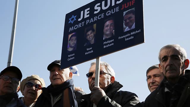 Familiares de las víctimas del ataque contra un supermercado kosher en Paris en 2015 sostienen un cartel durante su funeral. 