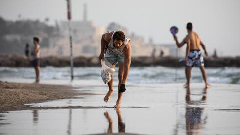 Melcer juntando colillas de cigarrillos en una playa de Tel Aviv. 