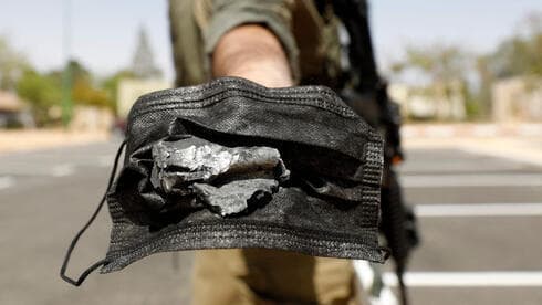 Un soldado muestra una esquirla del misil disparado desde Siria. 